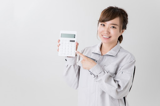 作業服を着た女性が電卓を持っている写真